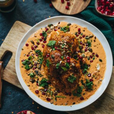 Delicious roasted cauliflower with vibrant garnet sauce and garnished with herbs, perfect for a healthy vegan meal.